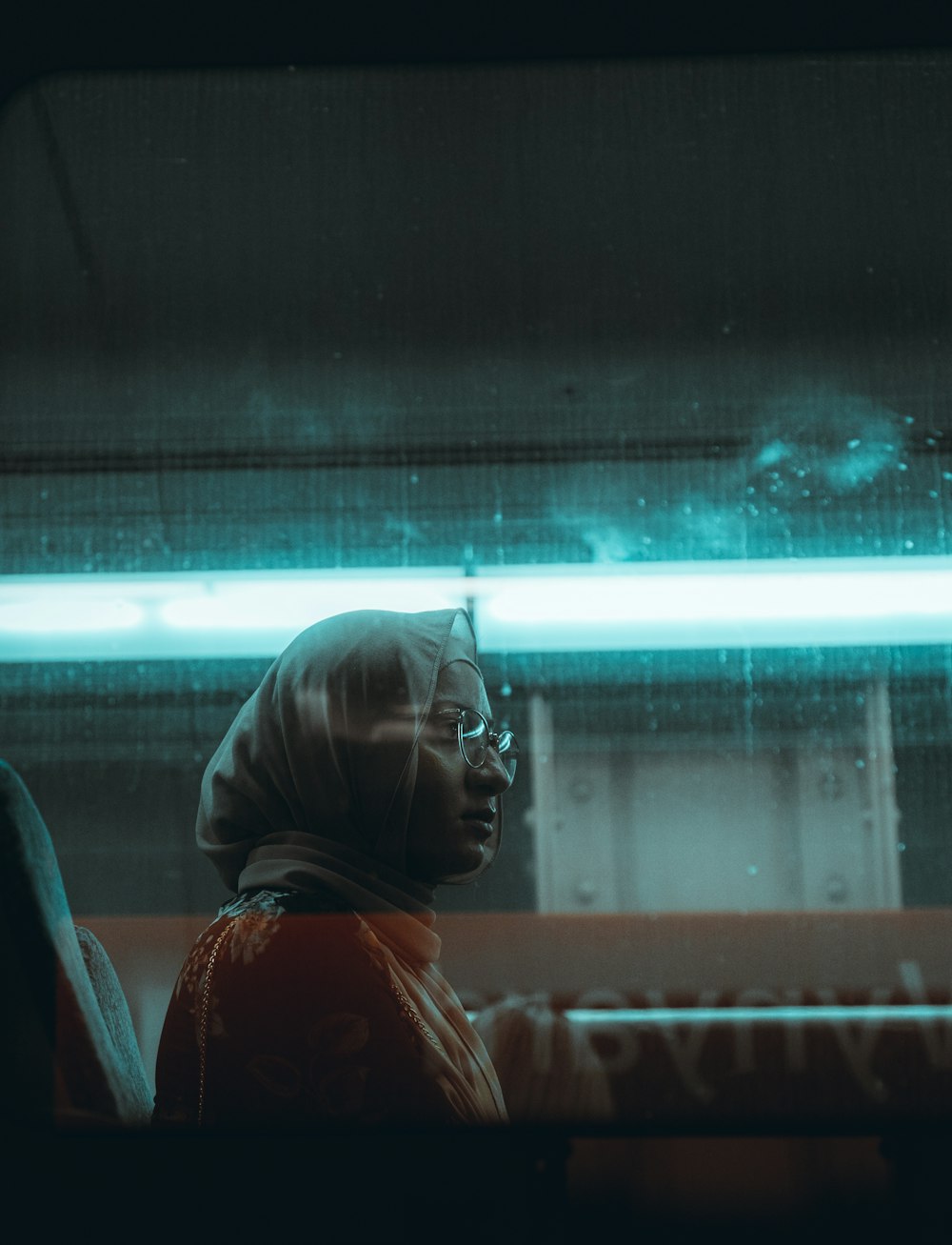 woman in orange and black jacket looking at glass window