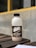 A bottle of 'Dare Double Espresso' is placed on a wooden surface. The label on the bottle displays coffee beans and text indicating it is a robusta and arabica coffee blend. In the background, there is a blurred outdoor wall with a yellow horizontal line.