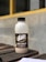 A bottle of 'Dare Double Espresso' is placed on a wooden surface. The label on the bottle displays coffee beans and text indicating it is a robusta and arabica coffee blend. In the background, there is a blurred outdoor wall with a yellow horizontal line.