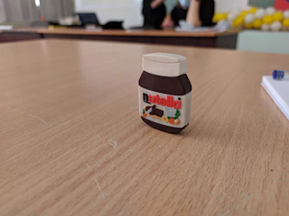 Close-up of homemade jars of rich hazelnut spread on a rustic wooden table.