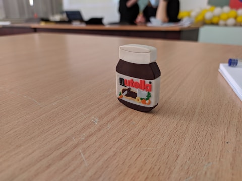 A close-up of a jar of chocolate hazelnut spread on a wooden table.