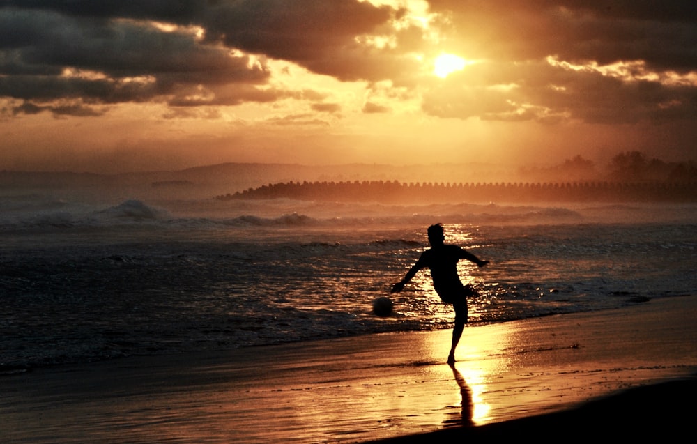 man in black shirt and shorts running on beach during sunset