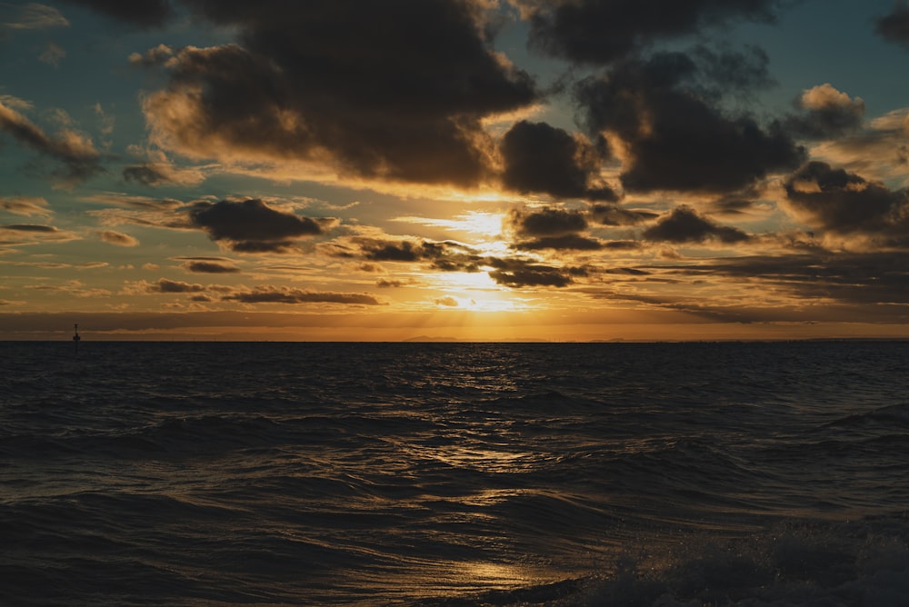 Cuerpo de agua bajo cielo nublado durante la puesta del sol