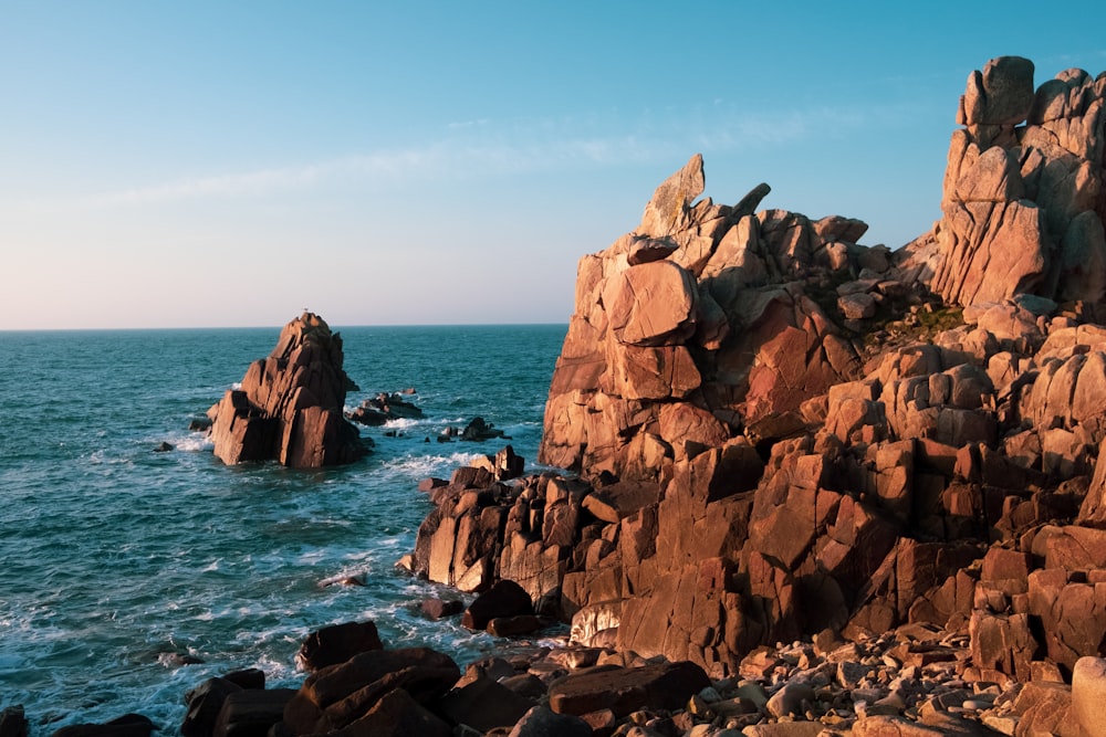 formação rochosa marrom no mar durante o dia