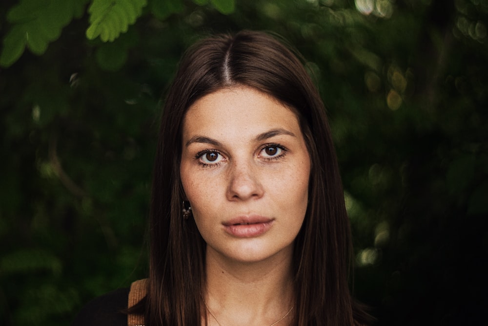 woman in brown shirt standing near green plant