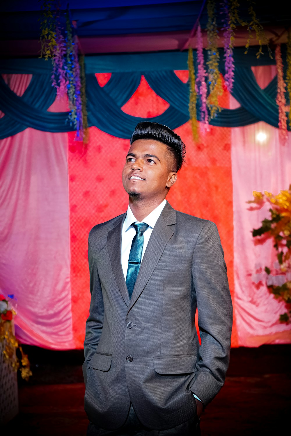 man in gray suit standing near red curtain