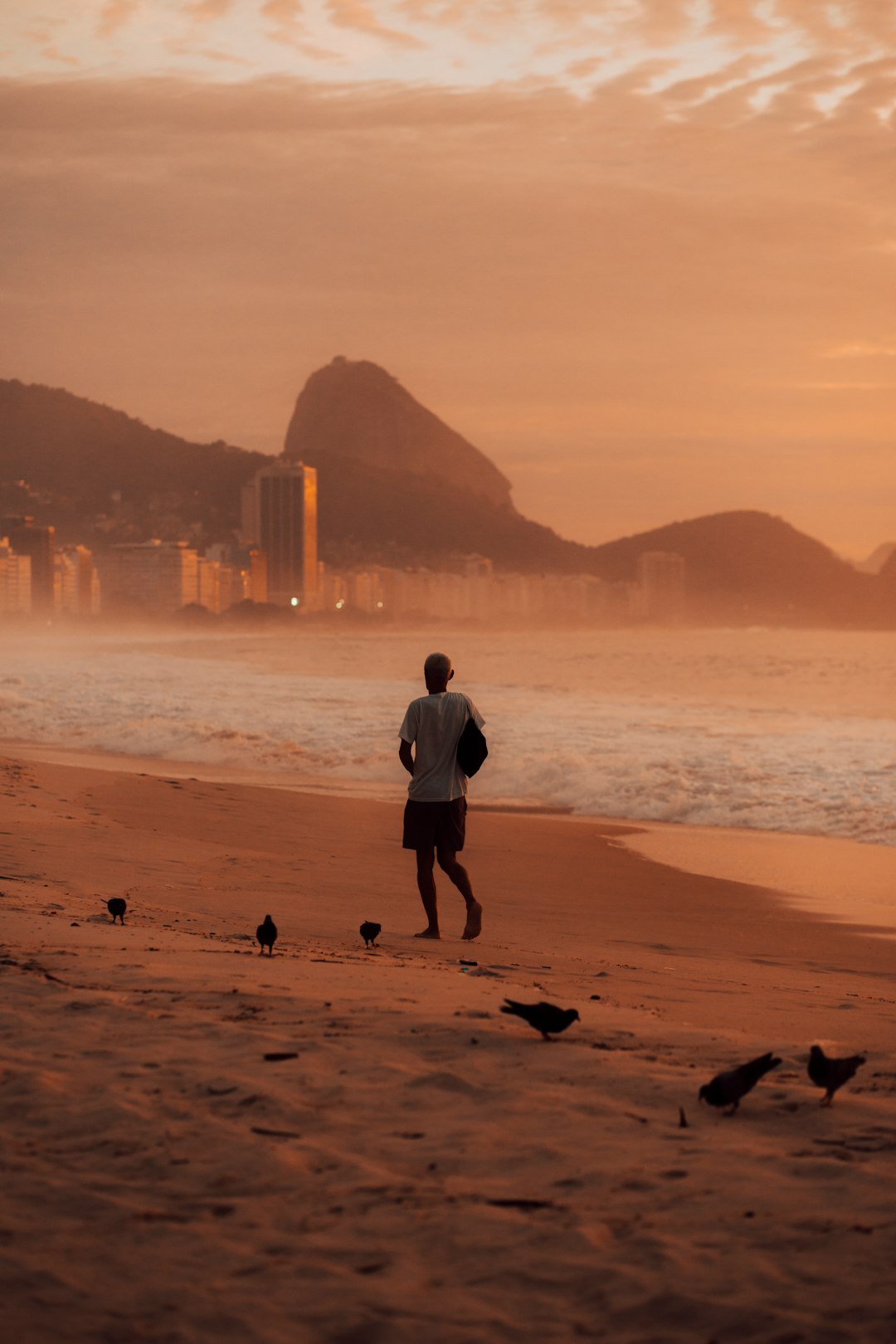 man in white t-shirt and black shorts standing on beach shore during daytime