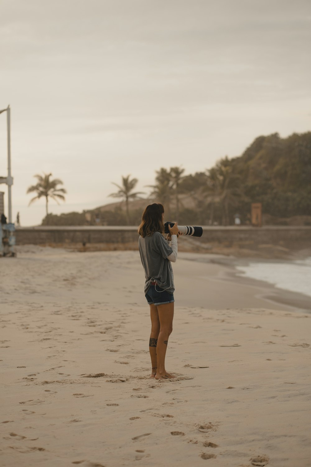 woman in white shirt and blue denim shorts standing on beach during daytime