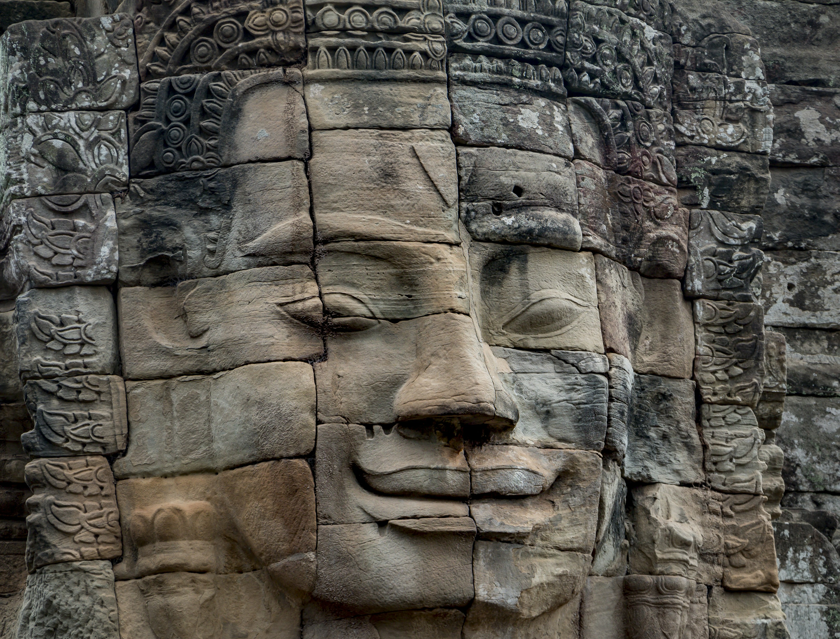 brown concrete statue during daytime, A face carved in stone blocks at Ankgor Was, Cambodia