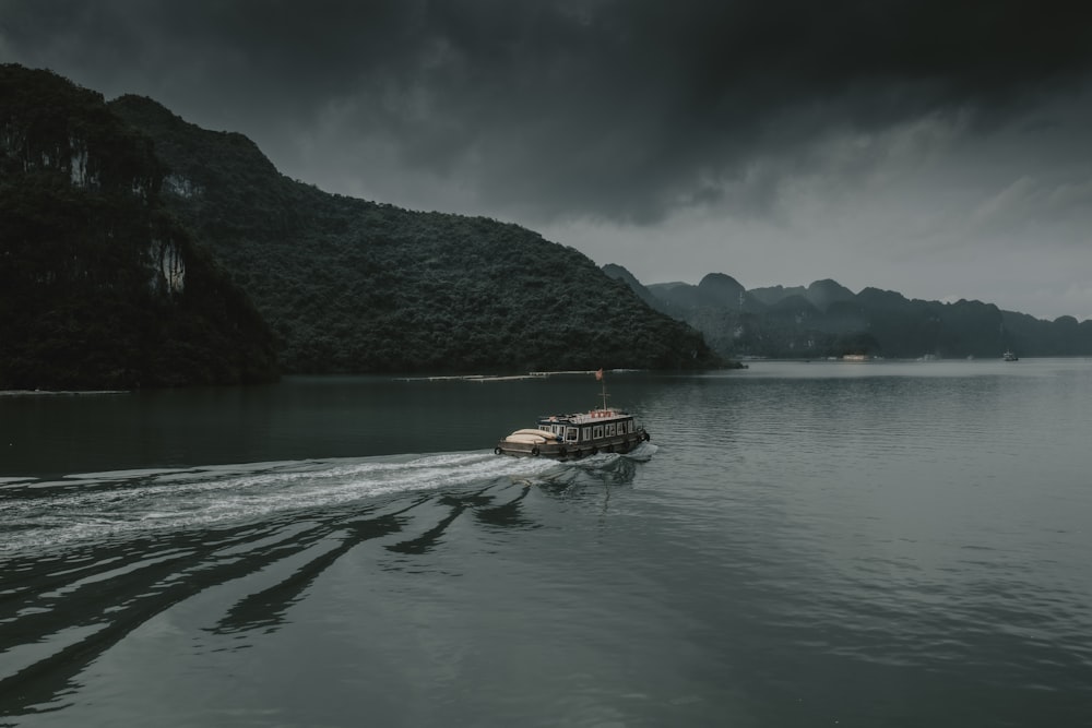 brown boat on body of water near mountain during daytime