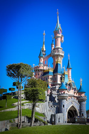 white and blue castle surrounded by green trees under blue sky during daytime