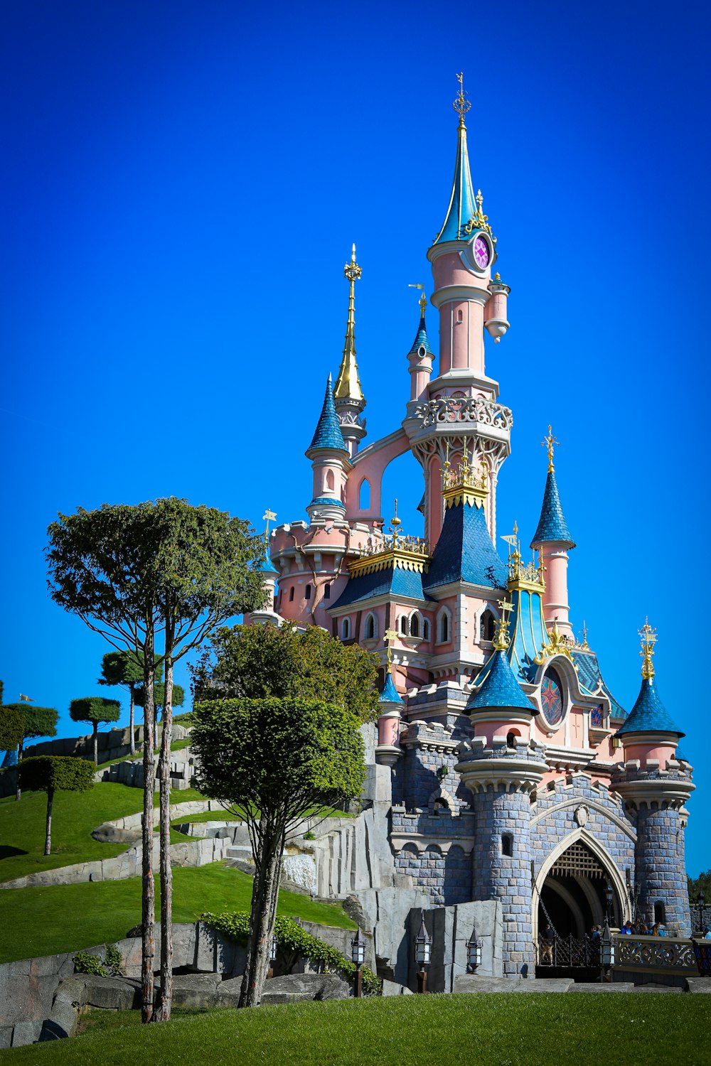white and blue castle surrounded by green trees under blue sky during daytime