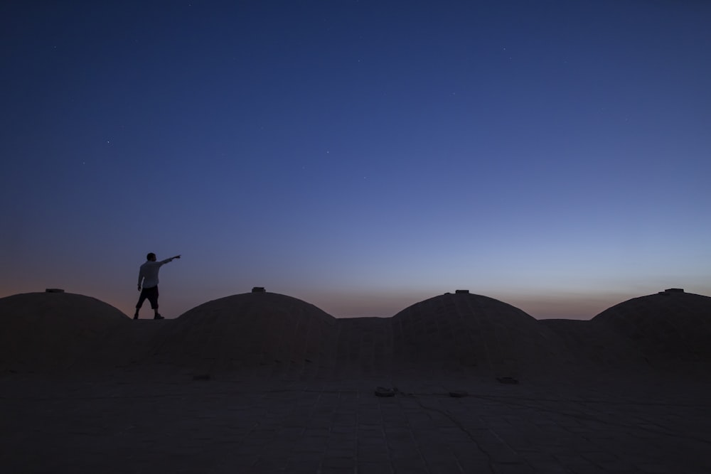 Silueta de la persona que salta en el desierto durante el día