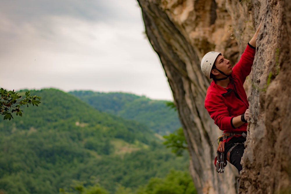 man in red jacket climbing on brown rock mountain during daytime
