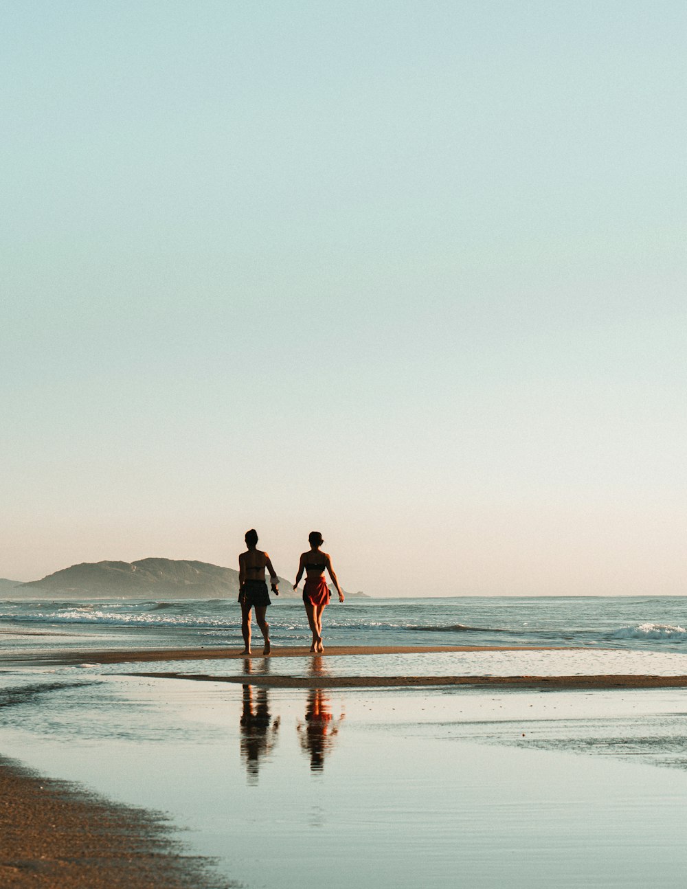 homem e mulher que caminham na praia durante o dia