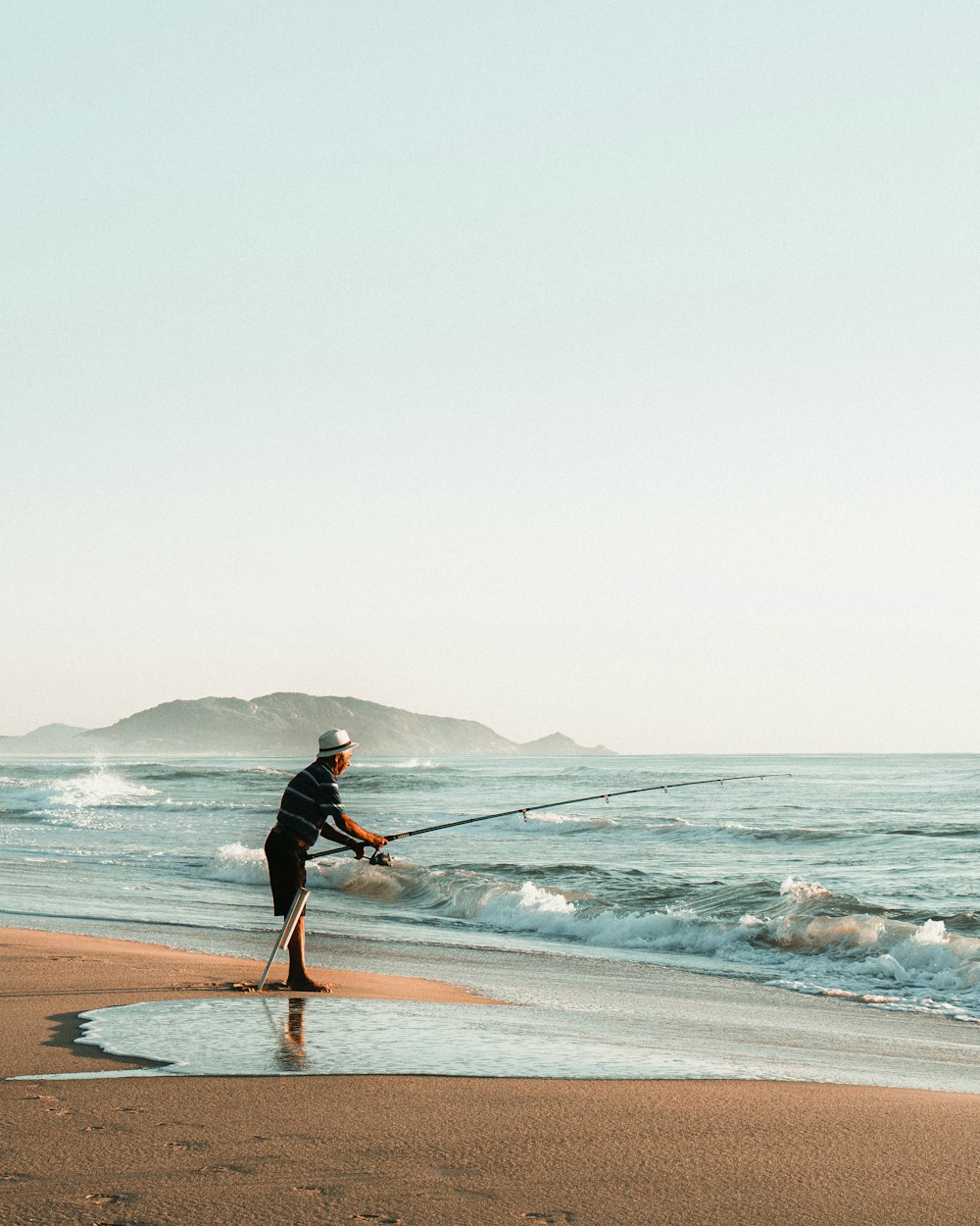 man in black jacket and black pants holding white surfboard walking on beach during daytime