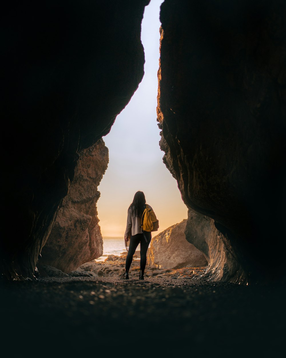 Donna in abito nero in piedi sulla formazione rocciosa marrone durante il giorno
