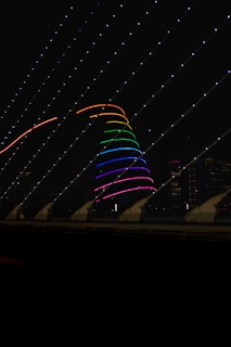 Close-up of the glowing neon twin primes spiral installation on the San Michele bell tower at dusk.