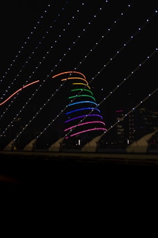 Close-up of the glowing neon twin primes spiral installation on the San Michele bell tower at dusk.