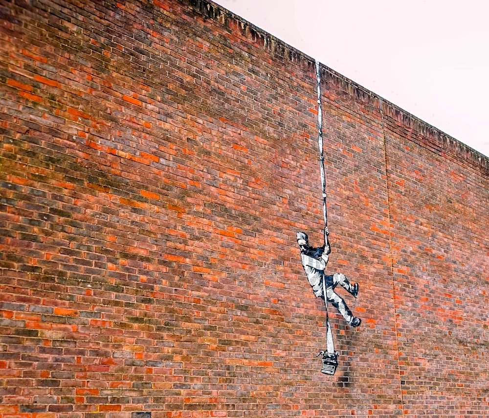 man in white and black jacket and black pants hanging on rope