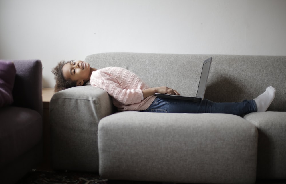 woman in pink and white stripe long sleeve shirt and blue denim jeans sitting on gray