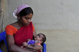 woman in red shirt carrying baby