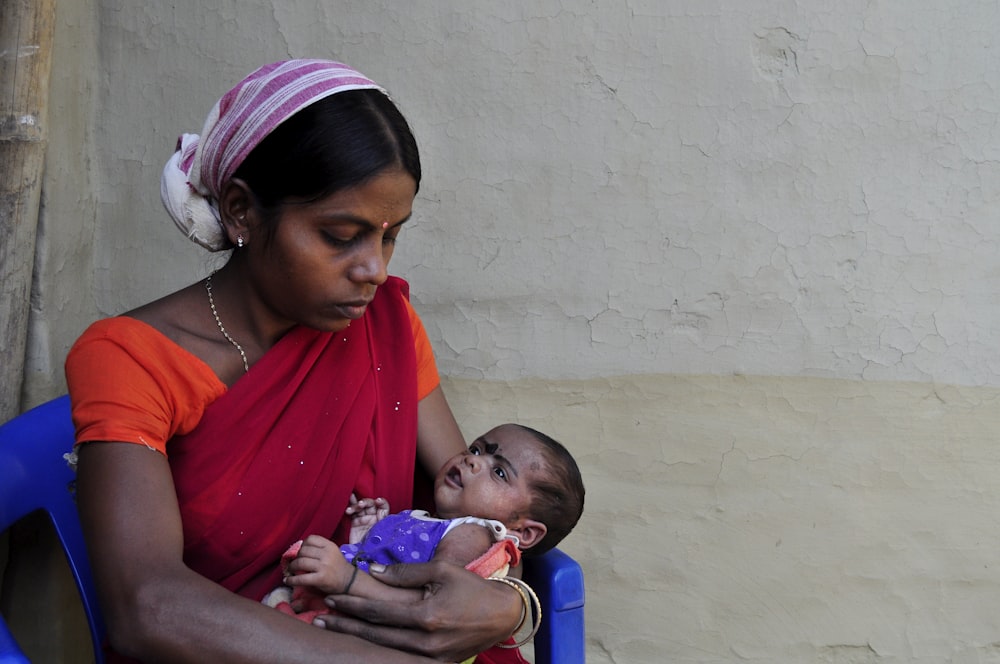 woman in red shirt carrying baby