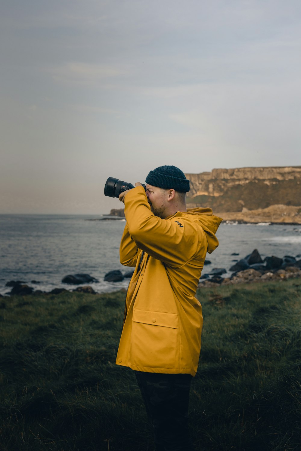 person in yellow hoodie holding black dslr camera