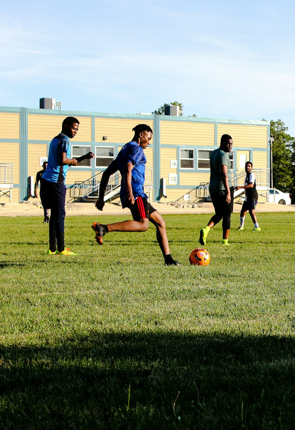 man in black t-shirt and blue denim jeans playing soccer during daytime