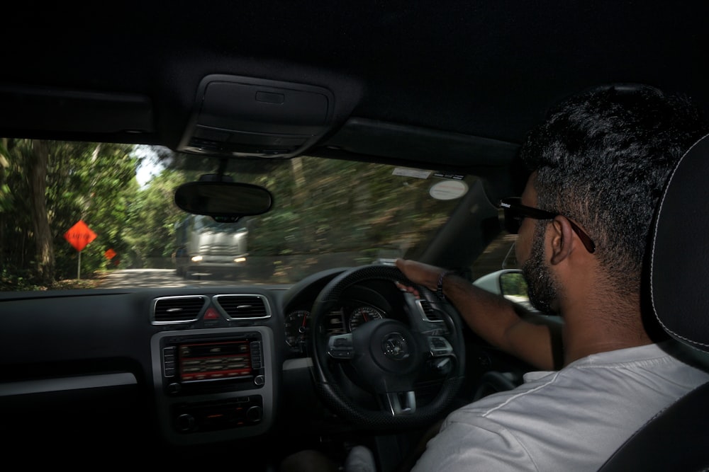 man in white shirt driving car