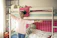 A happy child playing in a cozy, pastel-colored bedroom filled with playful furniture.