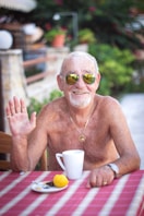 topless man wearing sunglasses sitting on chair