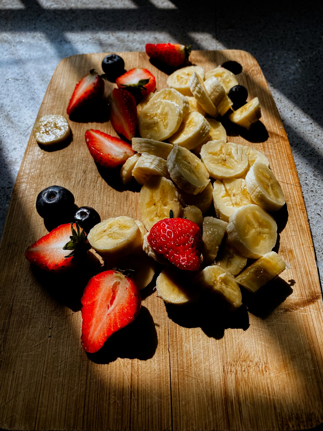 sliced apple and red fruit on brown wooden chopping board