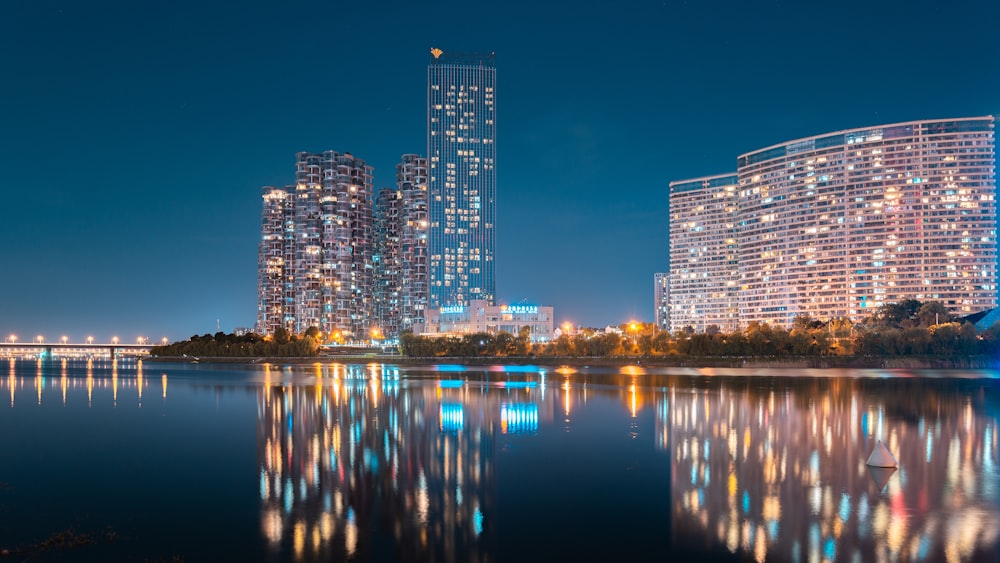 city skyline across body of water during night time