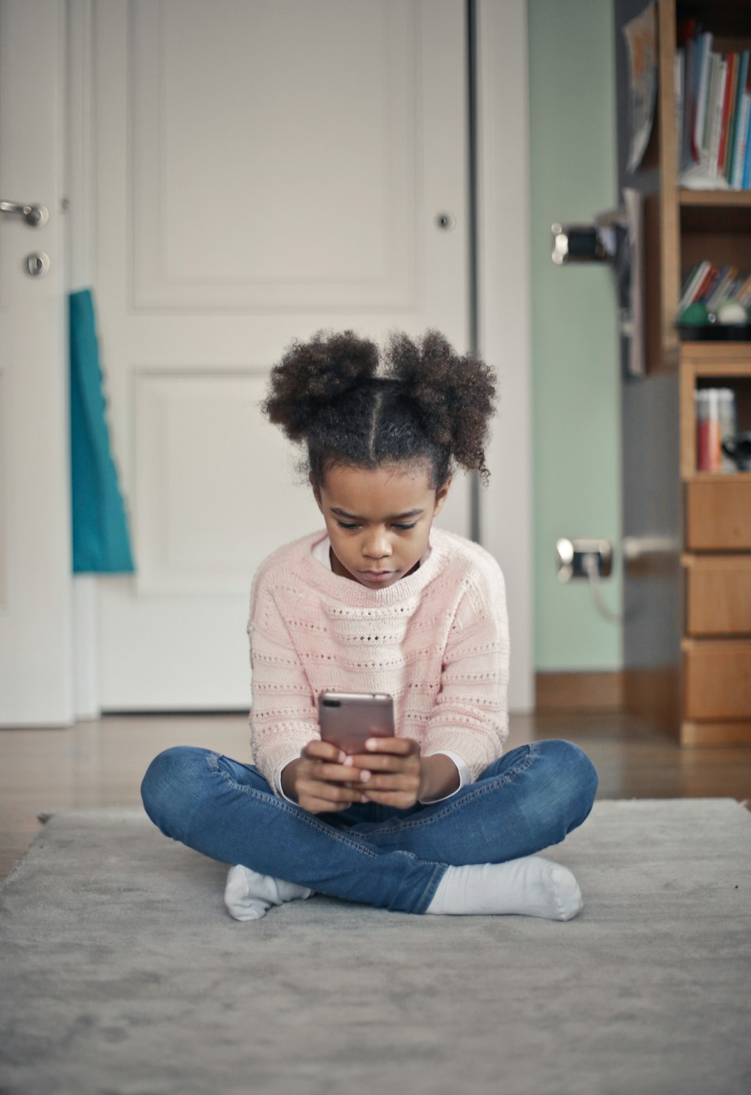 girl in white sweater and blue denim jeans sitting on floor