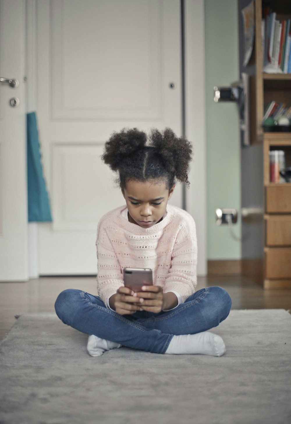 girl in white sweater and blue denim jeans sitting on floor