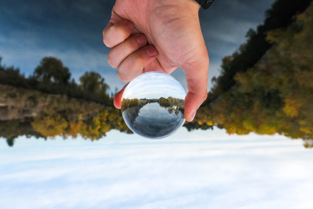 personne tenant une boule de verre transparent