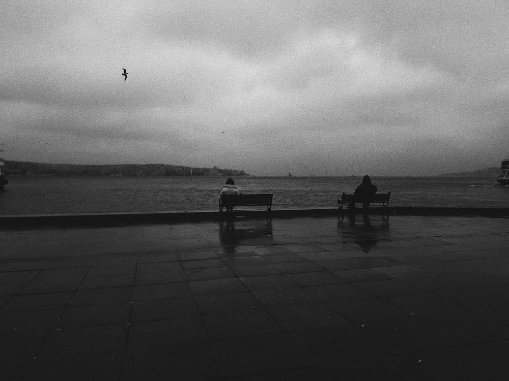 grayscale photo of person sitting on bench
