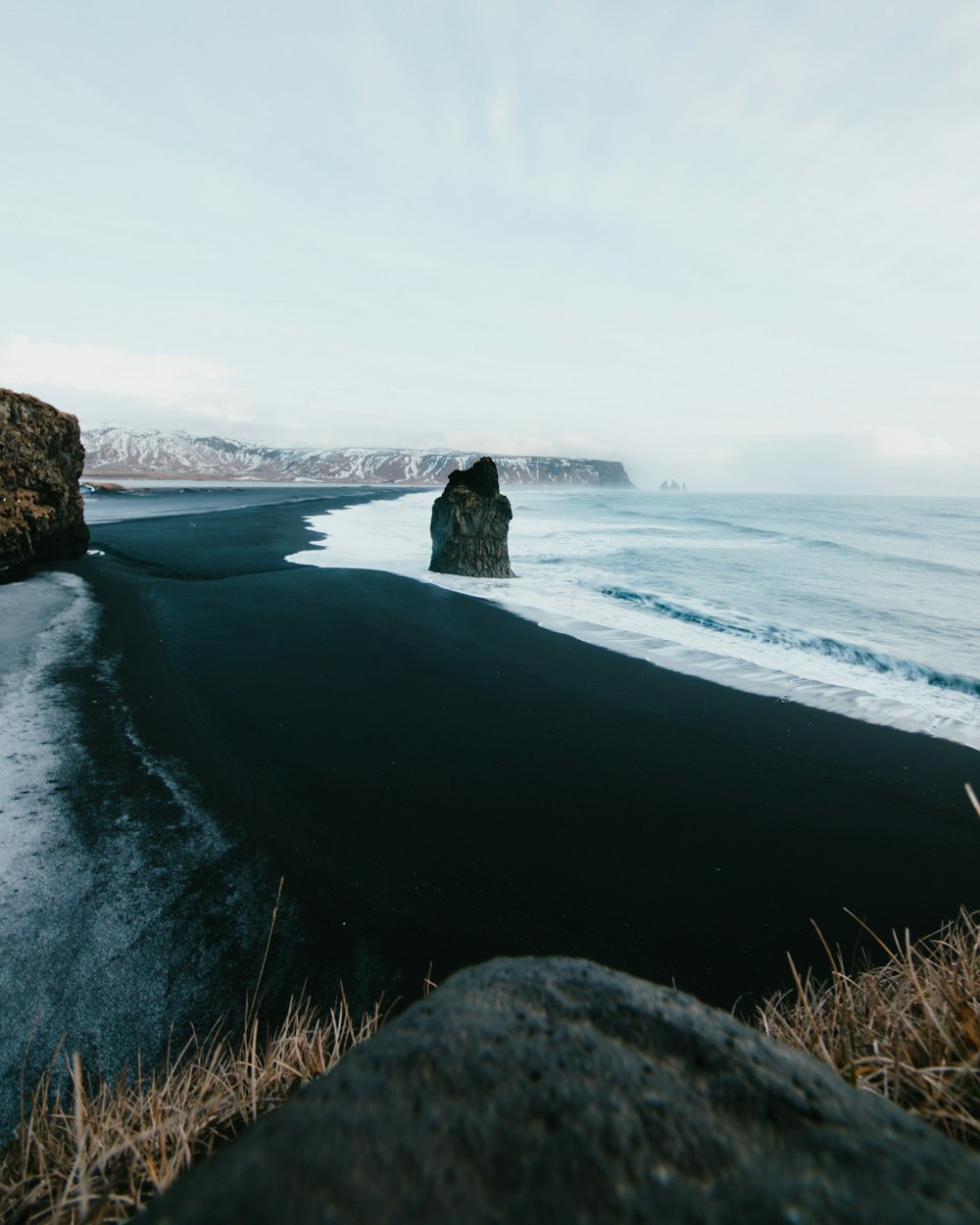 person sitting on rock near sea during daytime