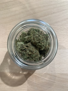A clean glass jar filled with golden CBD concentrate, placed on a wooden table with soft natural light.