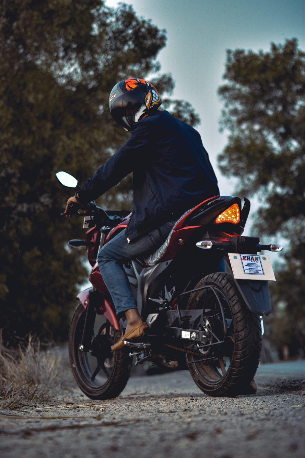 man in black jacket riding red and black sports bike
