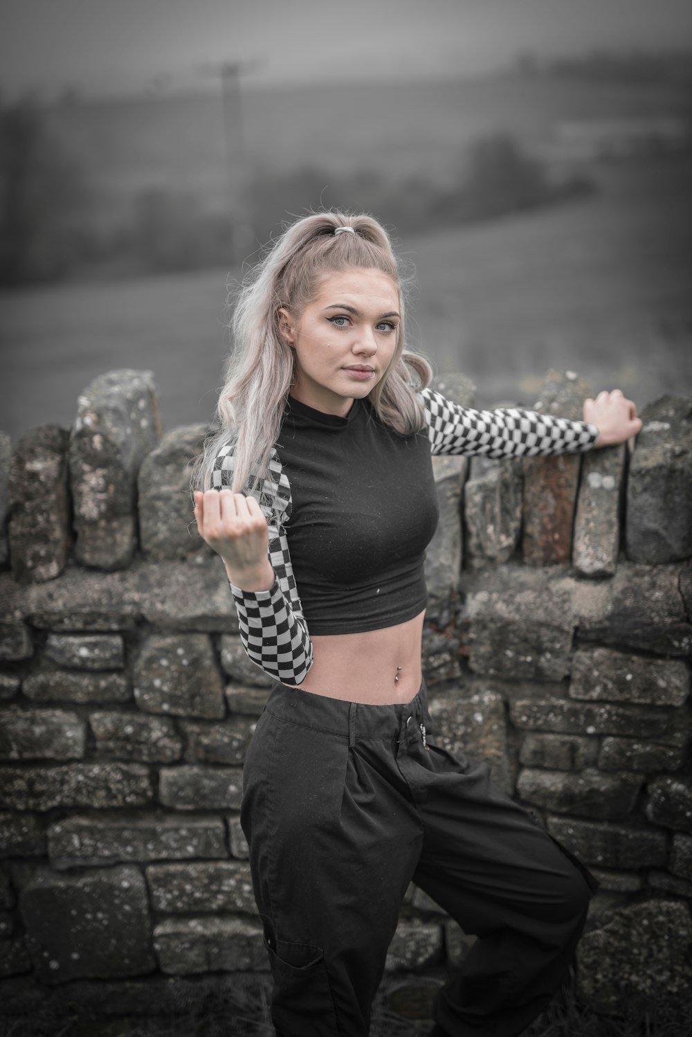 woman in black tank top and black pants standing beside brick wall during daytime