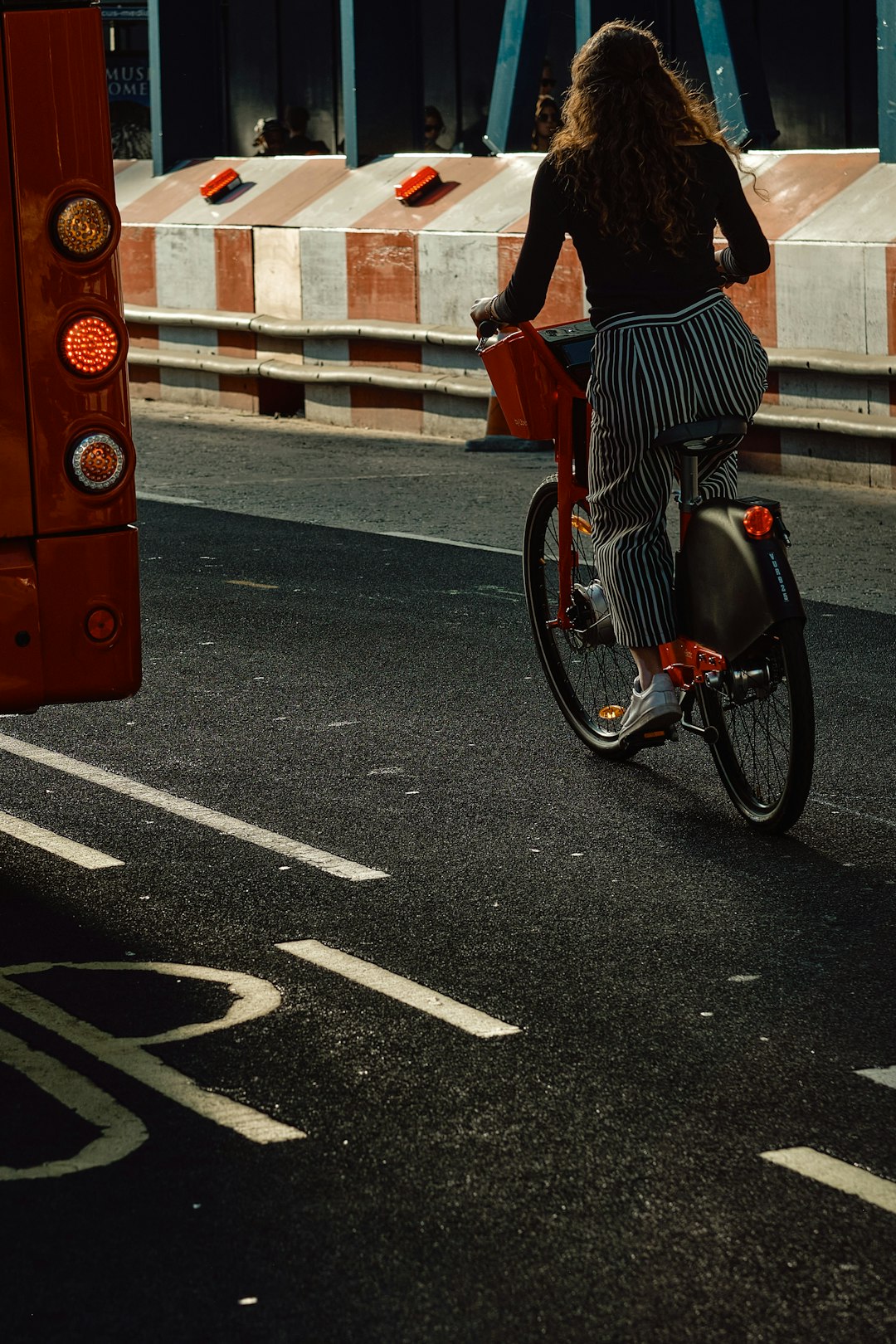 man in black and white stripe shirt and blue denim jeans riding on bicycle on road