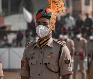 man in green and brown camouflage uniform with orange and yellow umbrella on his head