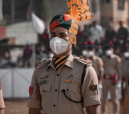 man in green and brown camouflage uniform with orange and yellow umbrella on his head