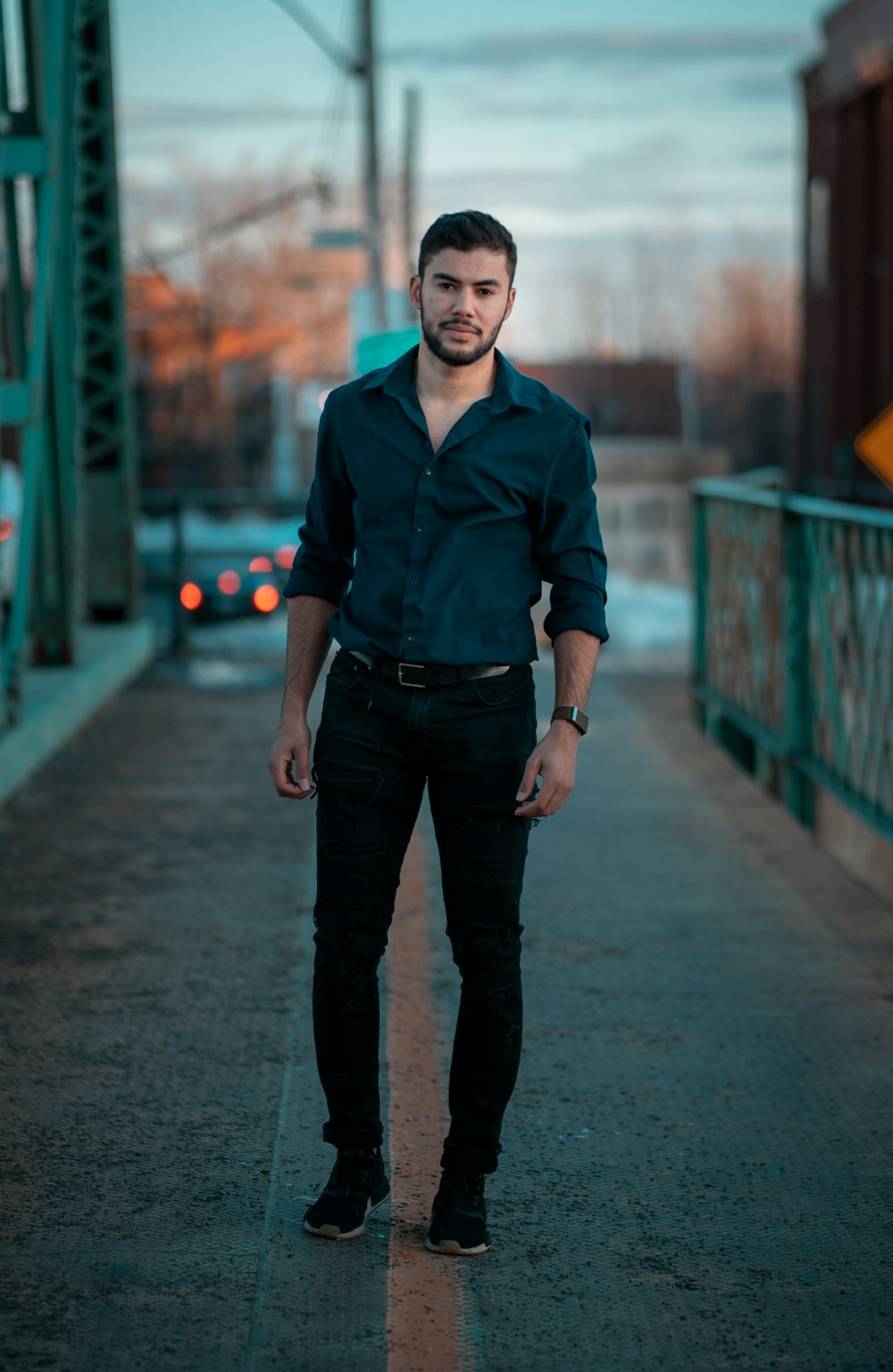 man in blue and red button up shirt standing on road during daytime