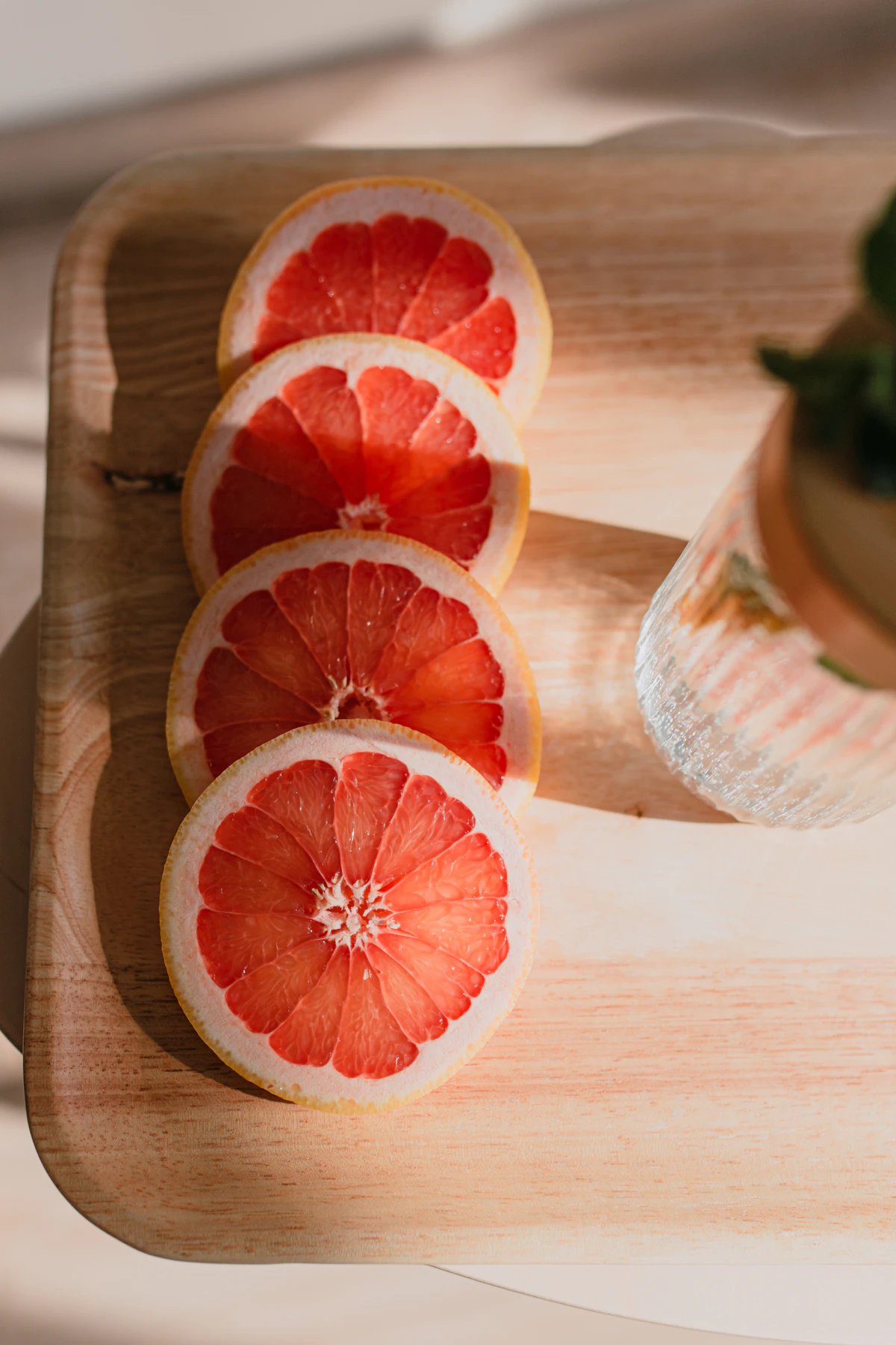 A red grapefruit cut in half on a wooden board