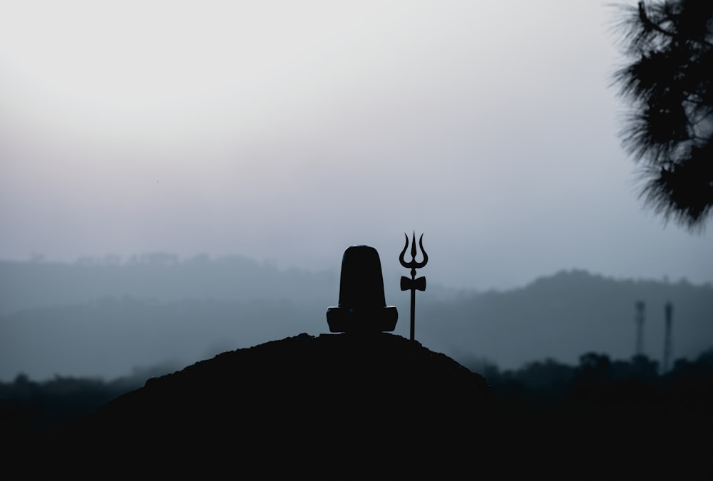 Silhouette eines Mannes, der tagsüber auf dem Gipfel des Berges steht