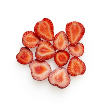 Close-up of vibrant freeze-dried strawberry slices arranged on a rustic wooden board.