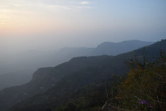 A serene mountain landscape with travelers enjoying a peaceful sunset overlooking lush green hills.